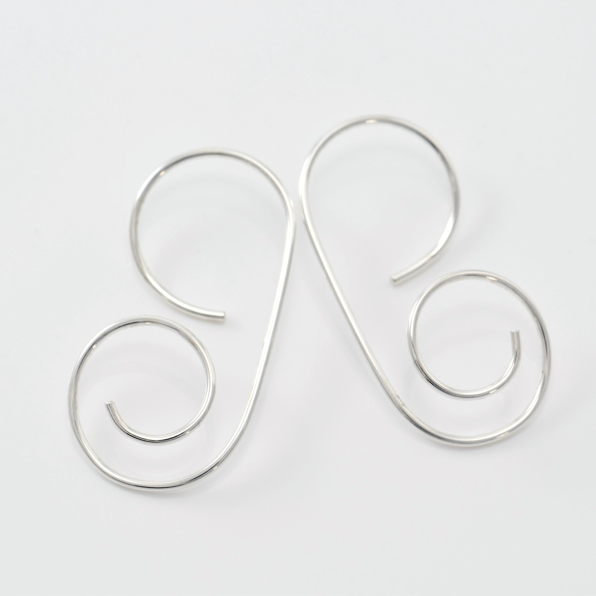 Pair of sterling G Spiral earrings on white background