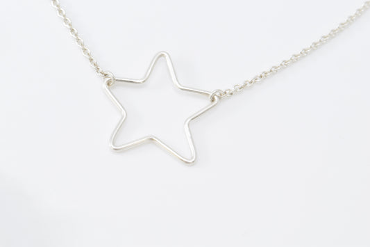 Silver star-shaped pendant inline on a chain against a white background