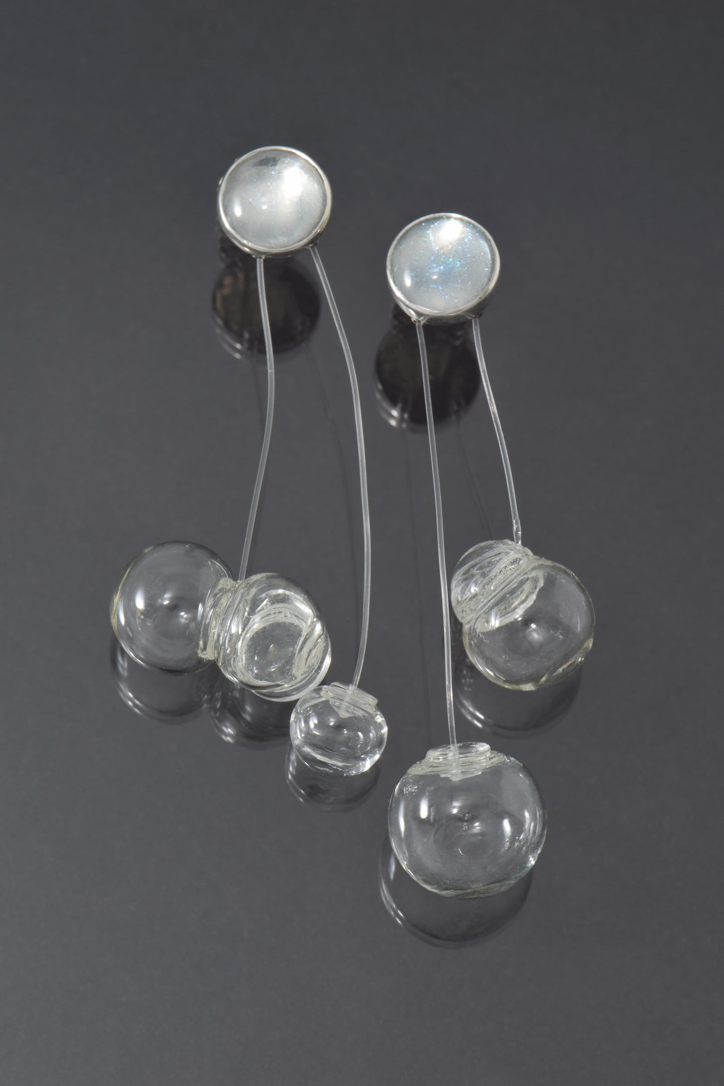 Silver earrings with glass bubbles on a dark background