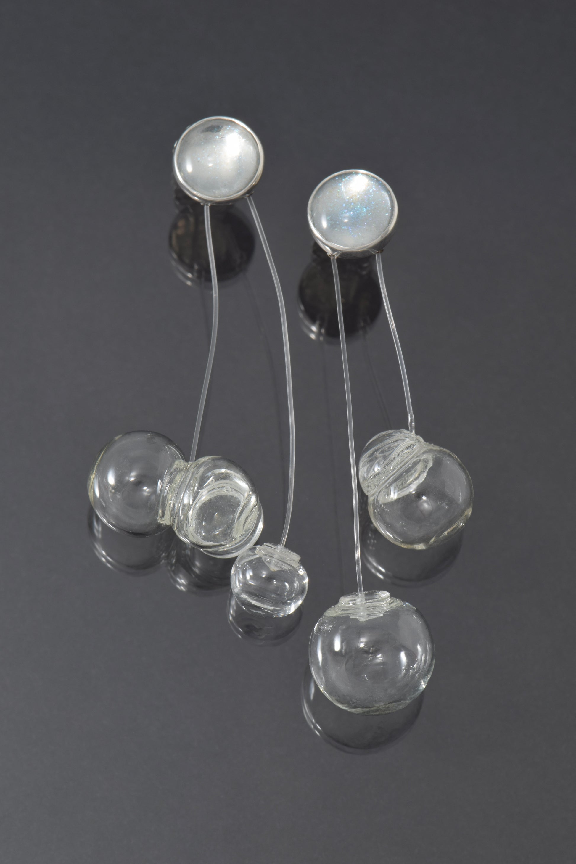 Silver earrings with glass bubbles on a dark background