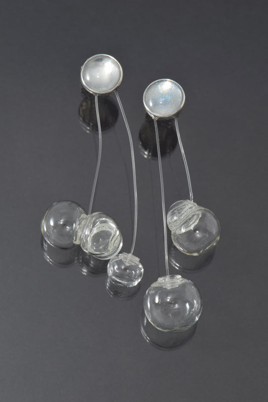 Silver earrings with glass bubbles on a dark background