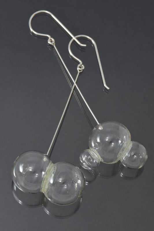 One pair and one triplet of glass bubbles hang at the end of a long, straight piece of silver on a fishhook style earwire.