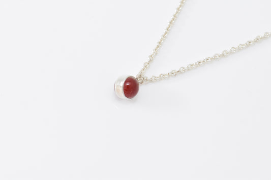 Lightweight cable chain with red carnelain spherical pendant on white background.