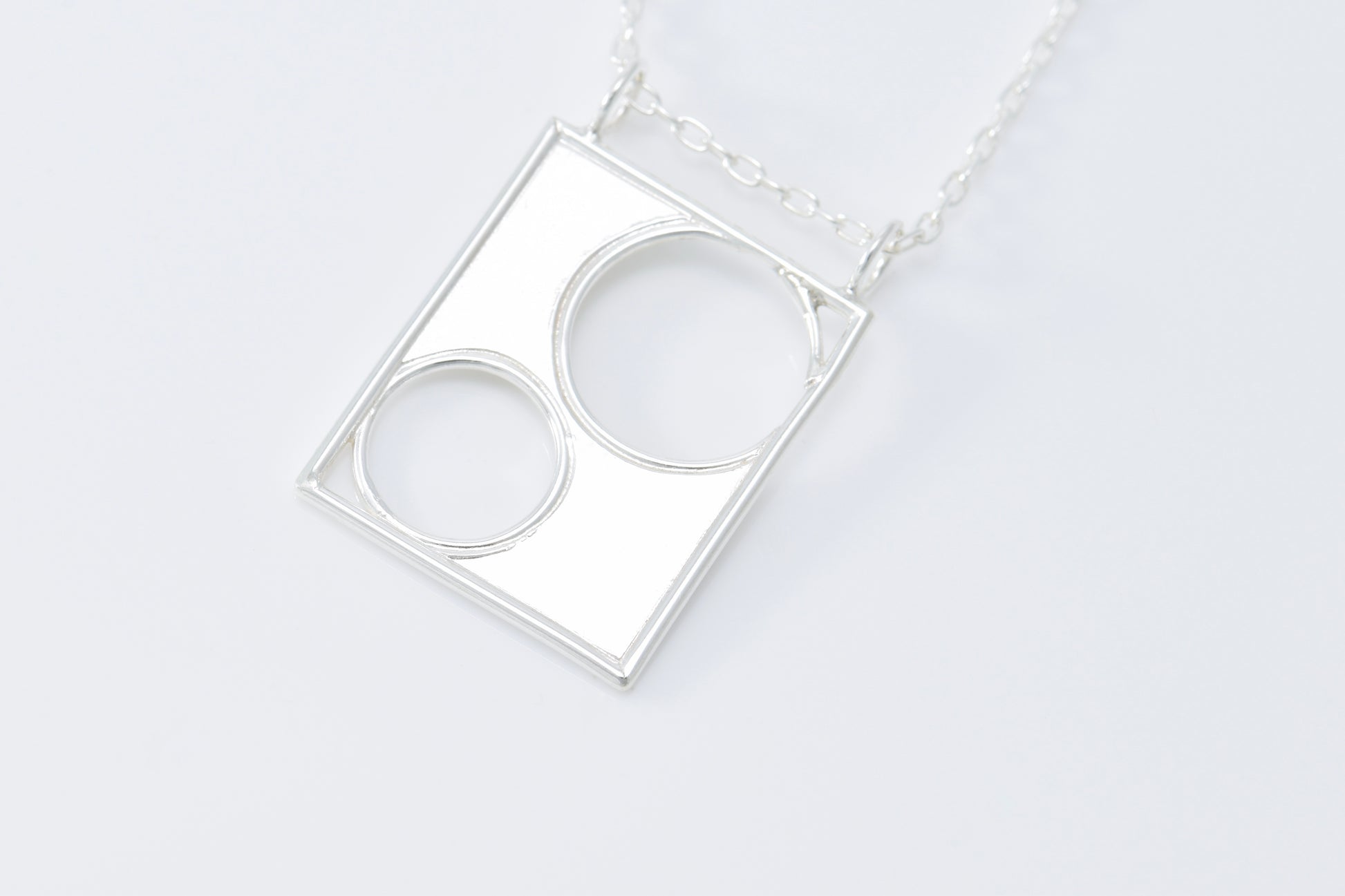 Silver necklace with a geometric pendant on a white background