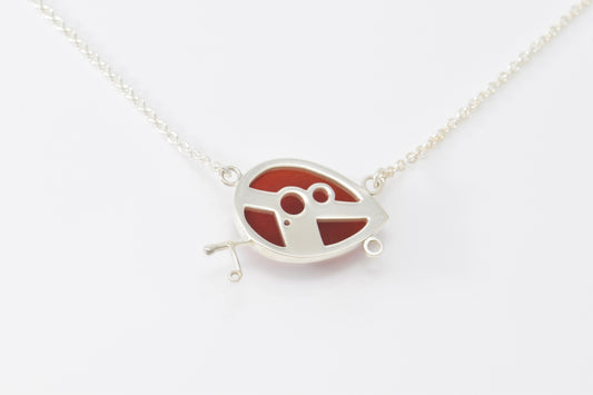 A red and silver teardrop camper inline on a sterling silver chain on a white background.