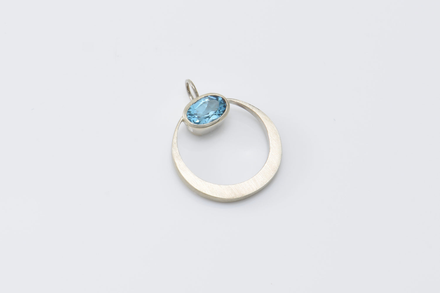 Silver ring with a blue gemstone on a light gray background