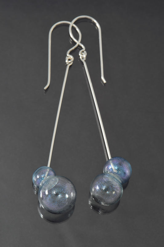 Lightly blue iridescent pairs of glass bubbles dangle at the ends of long, straight silver earrings.