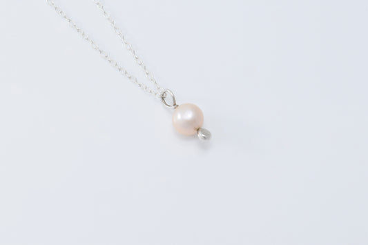 A single pearl pendant with a silver drop below it on a lightweight silver chain with a white background