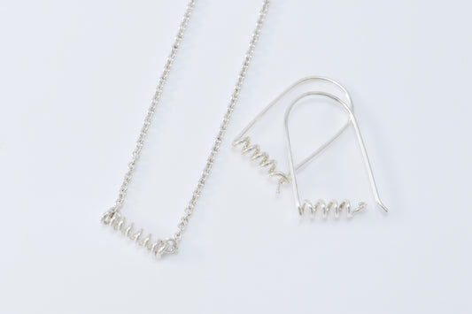 Necklace and earrings each with skinny spirals on white background