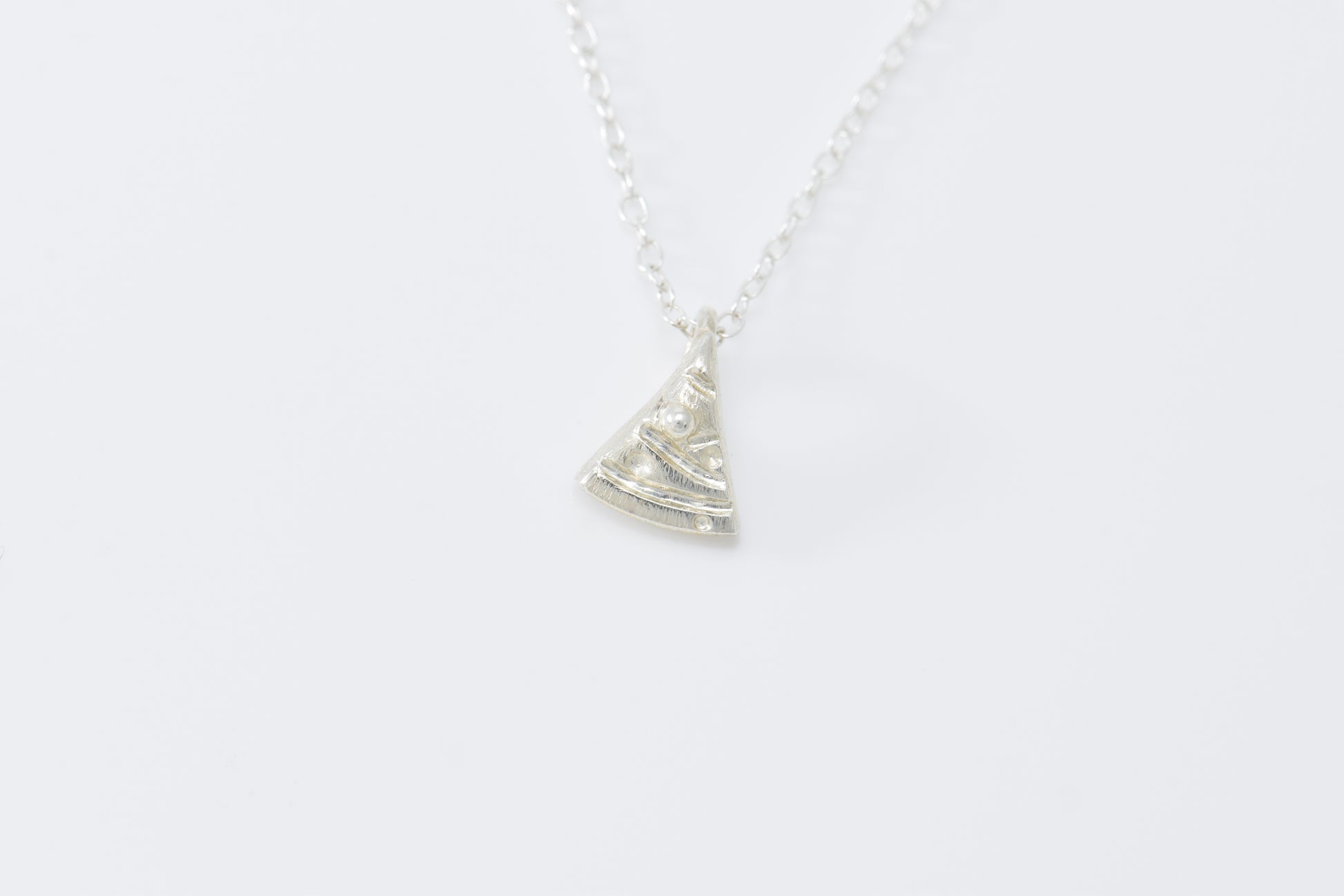 Tiny silver triangle Christmas tree with carved garland and ball ornaments on able chain.