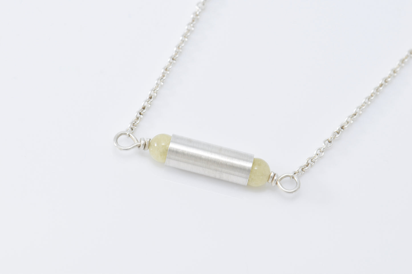 Necklace with yellow quartz on each end of a brush finished tube. 