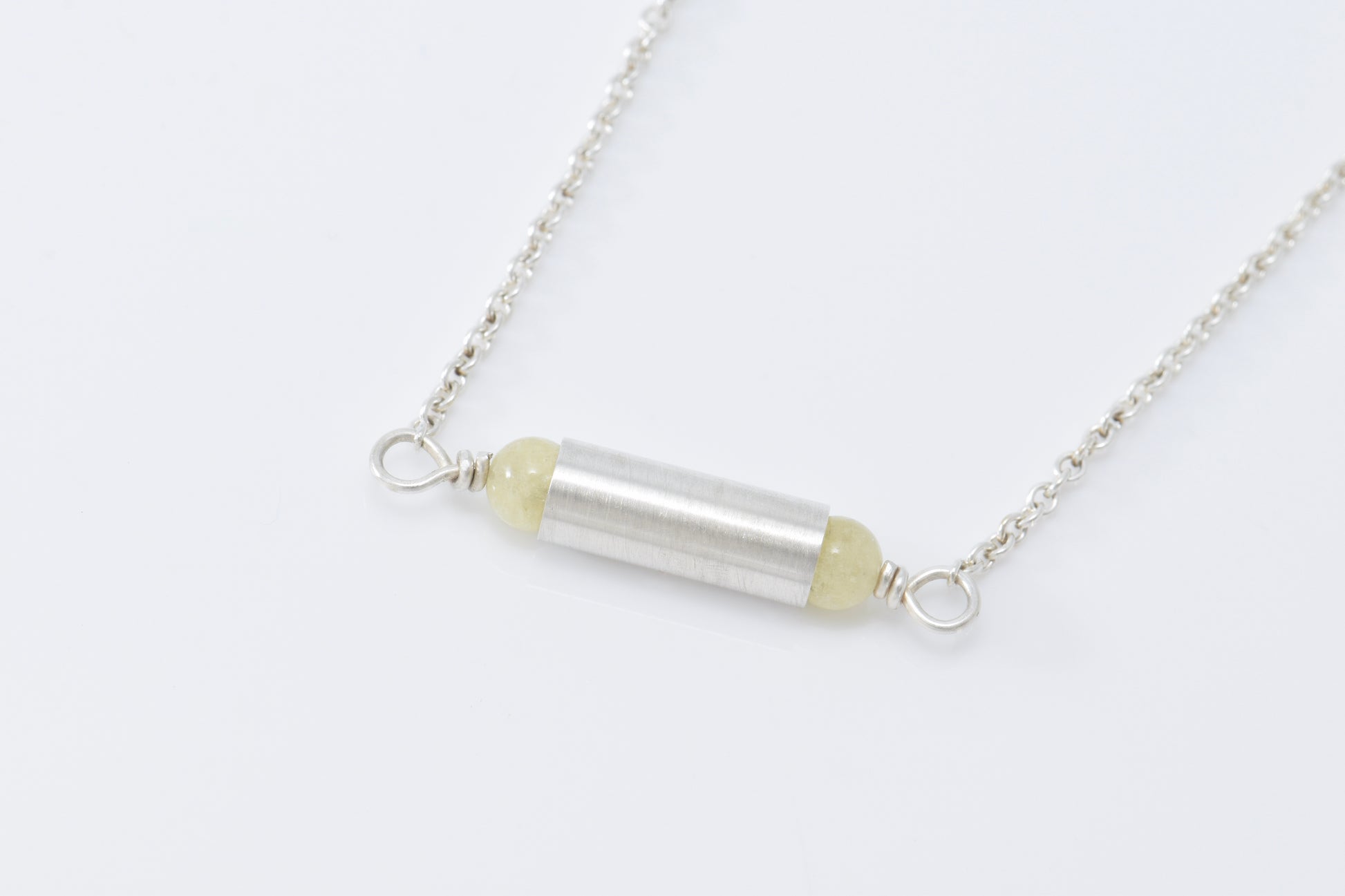 Necklace with yellow quartz on each end of a brush finished tube. 